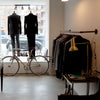 Kleiderstange für Montage an der Wand aus dunklen Wasserrohren zum Präsentieren von Kleidung in Geschäft