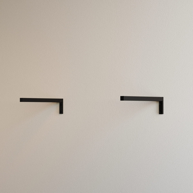 Beige Wand mit zwei minimalistischen schwarzen Regalhaltern, schlicht und modern angeordnet