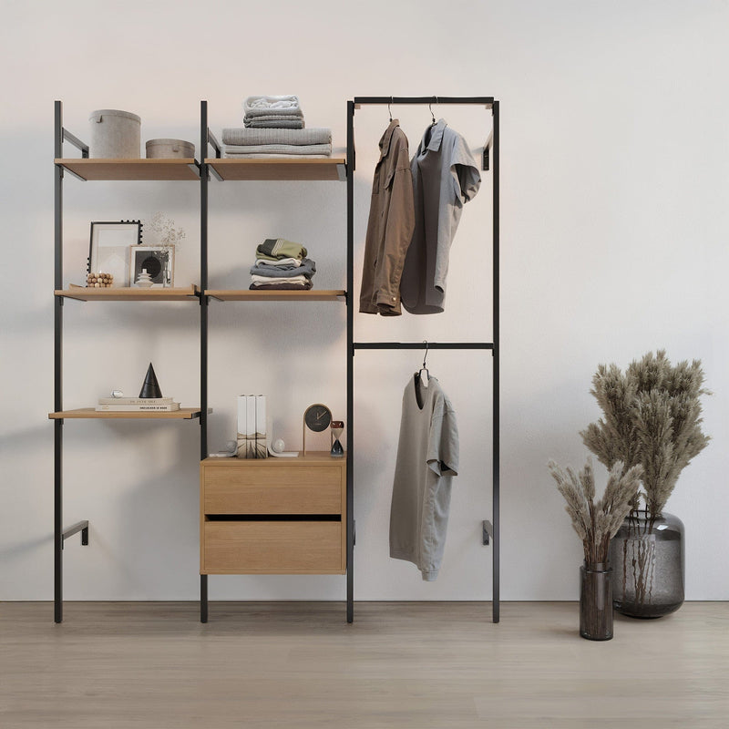 Offenes Regal mit hellen Holzböden, minimalistischer Kleiderständer mit zwei Hemden und Trockenblumen in Glasvasen auf hellem Boden