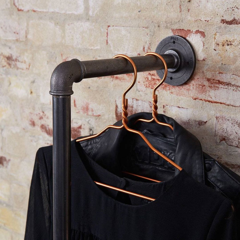 Kleiderstange aus dunklen Eisenrohren zum Aufhängen von Jacken und Kleidung auf Kleiderbügeln