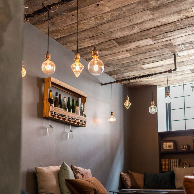 Kleiderstangen aus dunklen Eisenrohren zum Aufhängen von speziellen Glühbirnen in rustikaler Bar