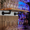 Wandmontierte Regale aus Eichenholz und dunklen Wasserrohren zur Aufbewahrung von Gläsern in Bar
