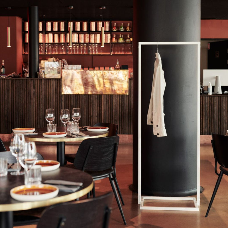 frei stehender Kleiderständer aus weißen Eisenrohren für Gäste als Garderobe im Restaurant