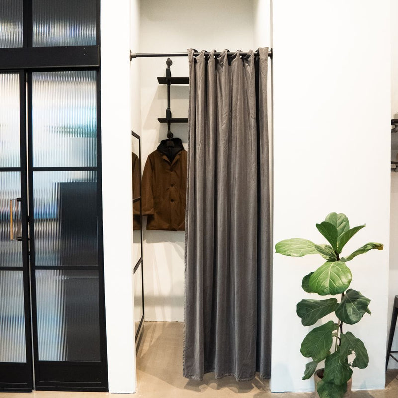 Umkleidekabine aus Kleiderstange zwischen zwei Wänden aus industriellen Wasserrohren