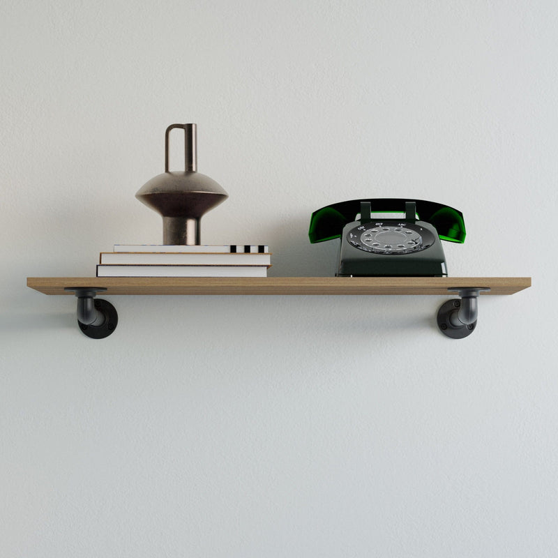 Hellgraue Wand mit einfacher Holzablage, auf der ein brauner Keramikkrug, drei Bücher und ein grünes Wählscheibentelefon stehen