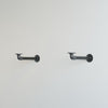 Helle Wand mit zwei schwarzen, industriellen Halterungen aus Metall im minimalistischen Stil montiert