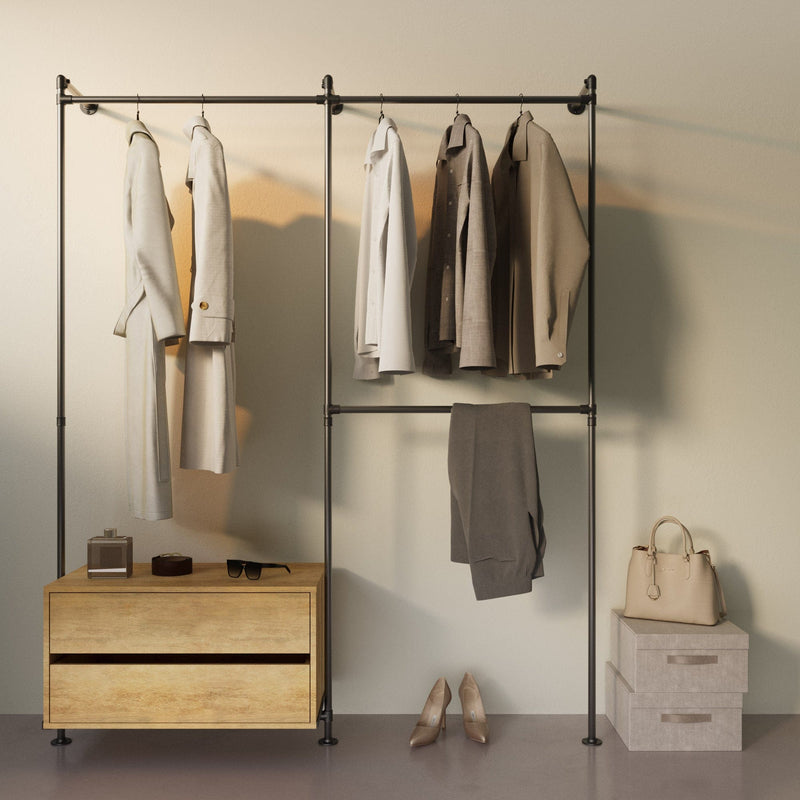 Minimalistisch gestalteter Kleiderständer mit hellen Jacken, Holzkommode, Schuhen und cremefarbenen Accessoires vor hellem Hintergrund