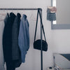 frei stehender Kleiderständer aus dunklen Eisenrohren im industriellen Design mit Platz für Kleidung und Taschen