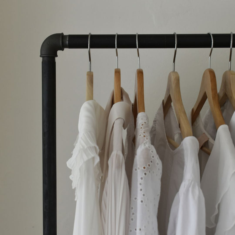 Kleiderstange aus dunklen Eisenrohren im industriellen Design als offener Kleiderschrank